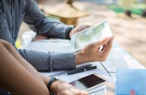 Pessoas analisam informações em um tablet sobre uma mesa com anotações e celulares, representando a consulta a boletins econômicos para tomada de decisões financeiras bem informadas.