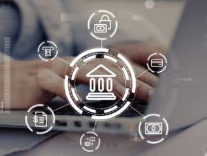 Pessoa digita em um notebook com ícones digitais flutuando ao redor, representando os diversos serviços e tecnologias integradas ao sistema bancário moderno e digitalizado.